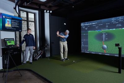 a man golfing indoors on a golf simulator