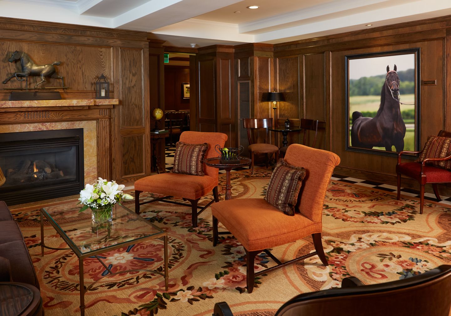 The interior of the American Club with a fireplace and a portrait of a horse on the wall
