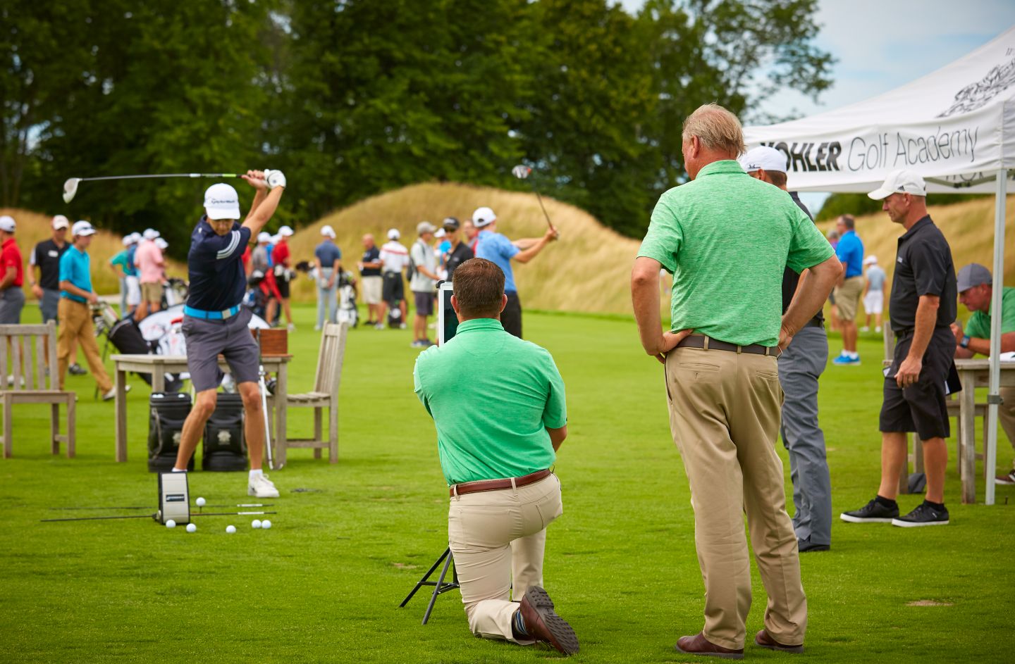 Golfers receiving golf instruction at golf course practice facility