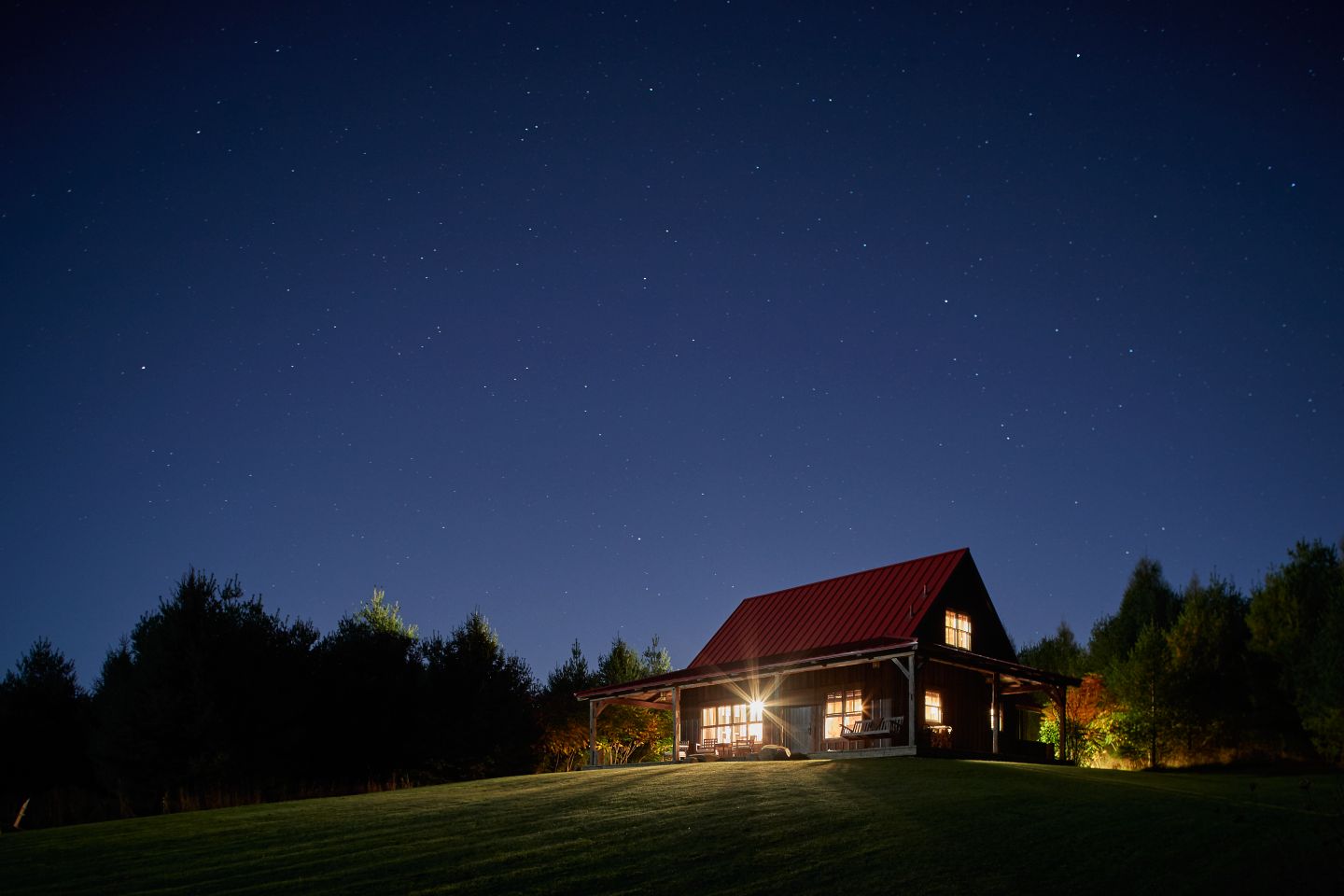 A clear night sky with the Sandhill Cabin lit up in the distance