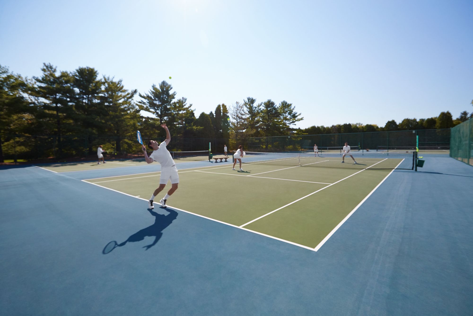 a tennis player serving on an outdoor tennis court