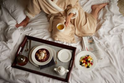 a lady eating having room service food on the bed