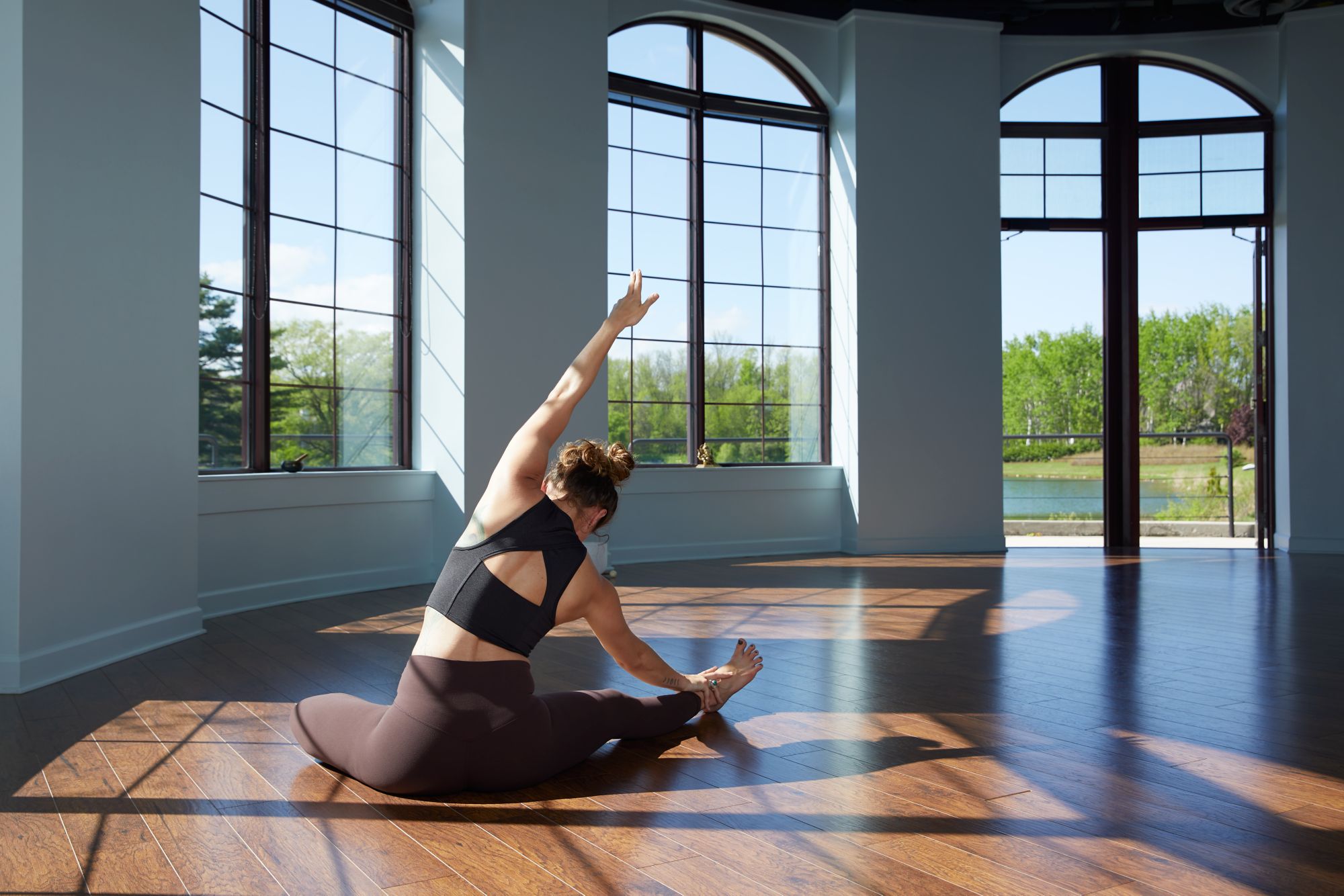 a woman sitting on the ground doing yoga with windows in the background