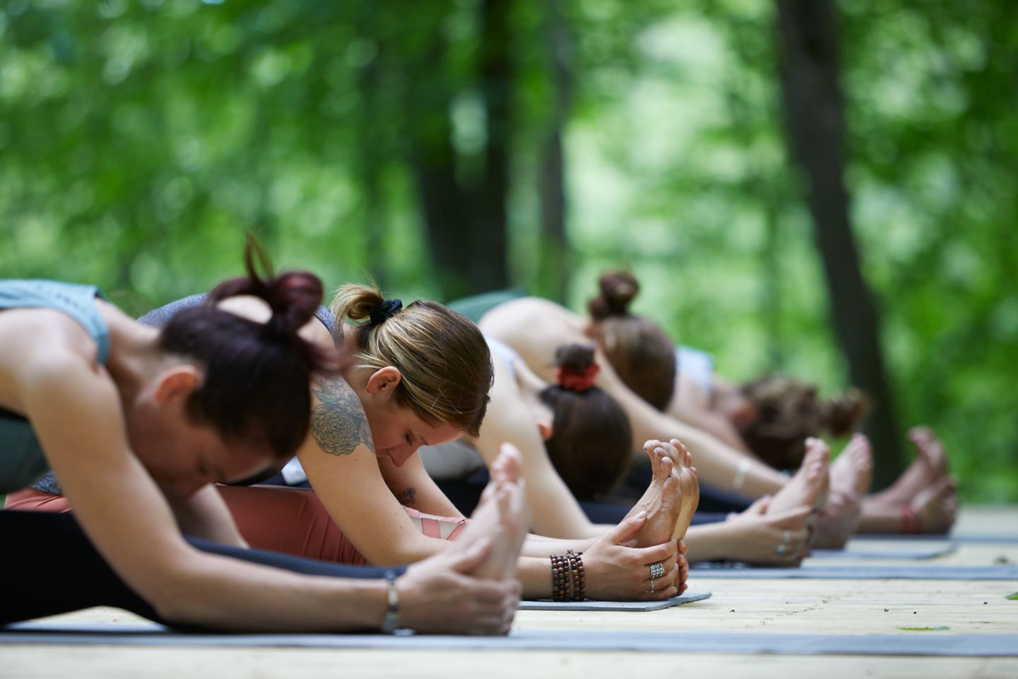 a group of women stretching on a wood deck in the woods