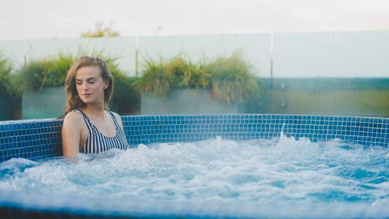 Woman relaxing in rooftop hot tub at Kohler Waters Spa, St Andrews