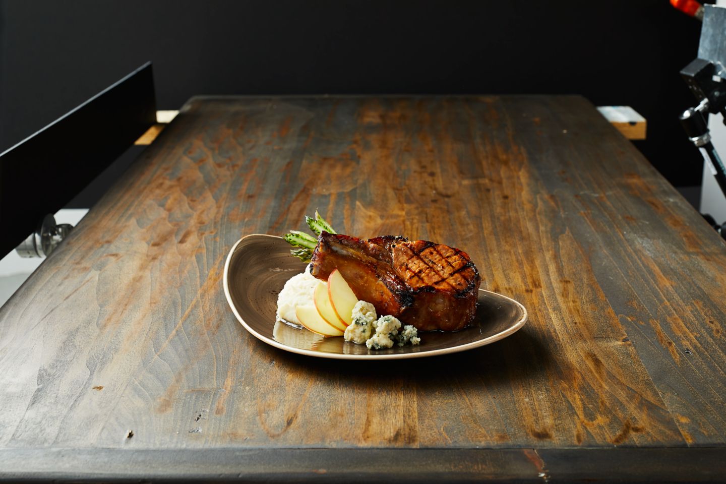a pork-chop on a plate sitting on a wooden table