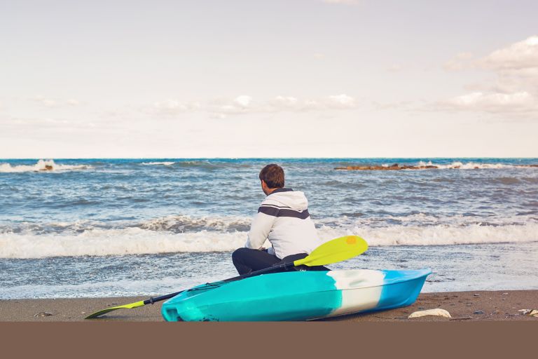 Man sitting on a kayak on the beach