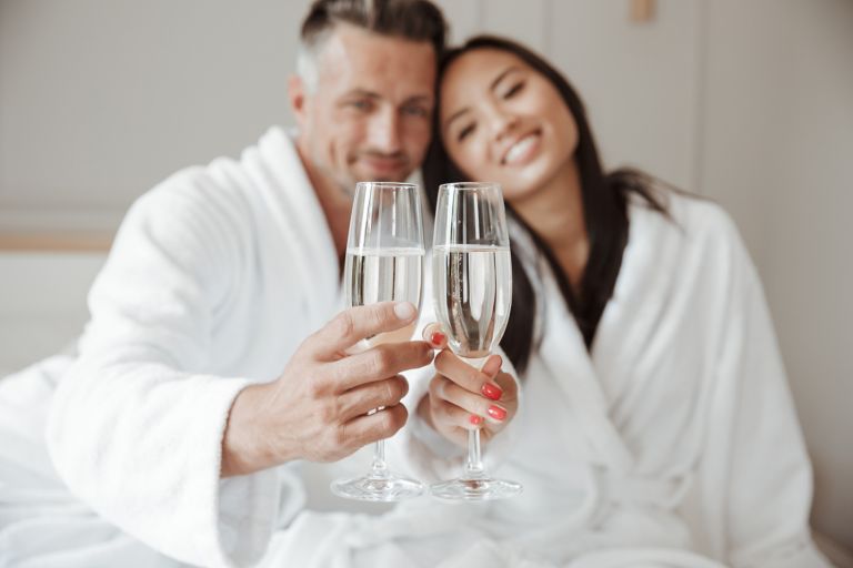 Man and woman enjoying a glass of prosecco in their bathrobes