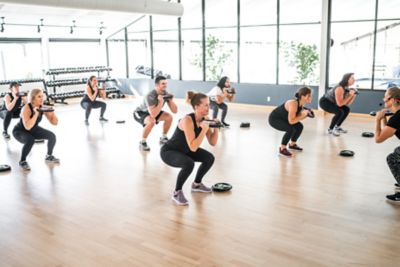 a group of people doing squats in an indoor workout studio