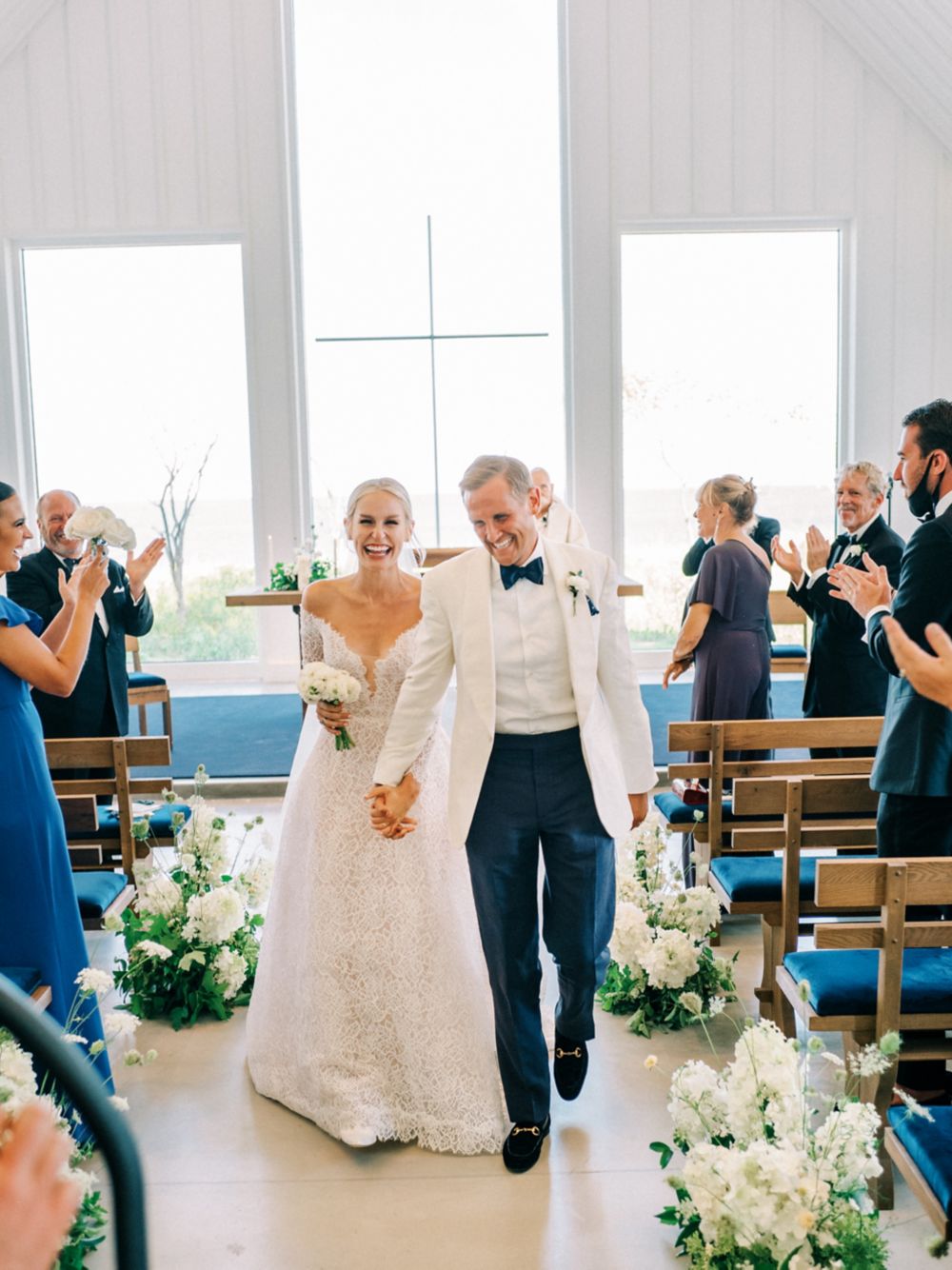 a bride and groom walking down the aisle smiling after a wedding ceremony