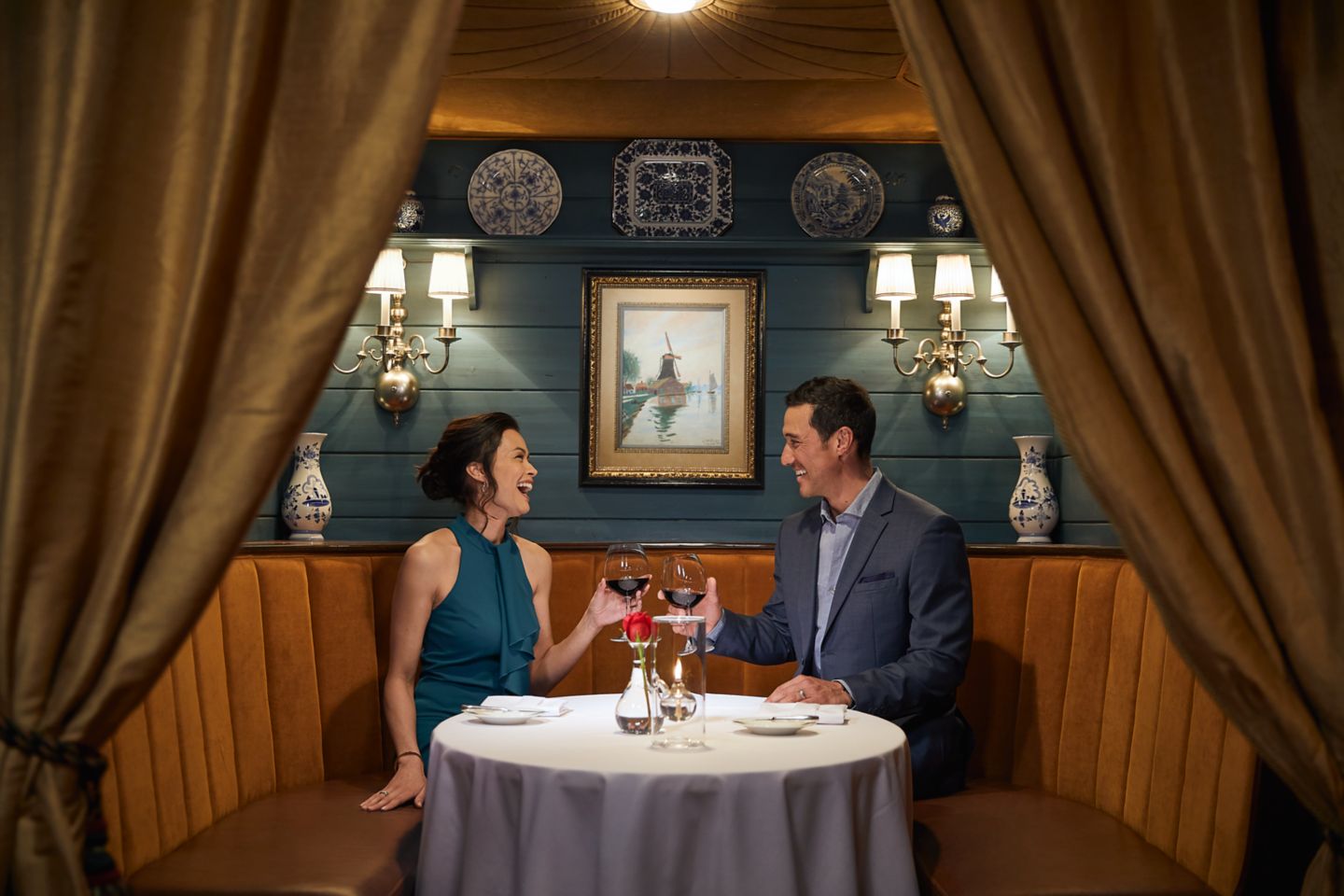 a couple enjoying dinner, drinking wine and laughing in a dining booth at the Immigrant Restaurant