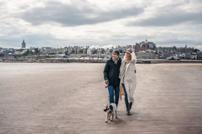 Man and woman walking a dog on West Sands Beach, St Andrews
