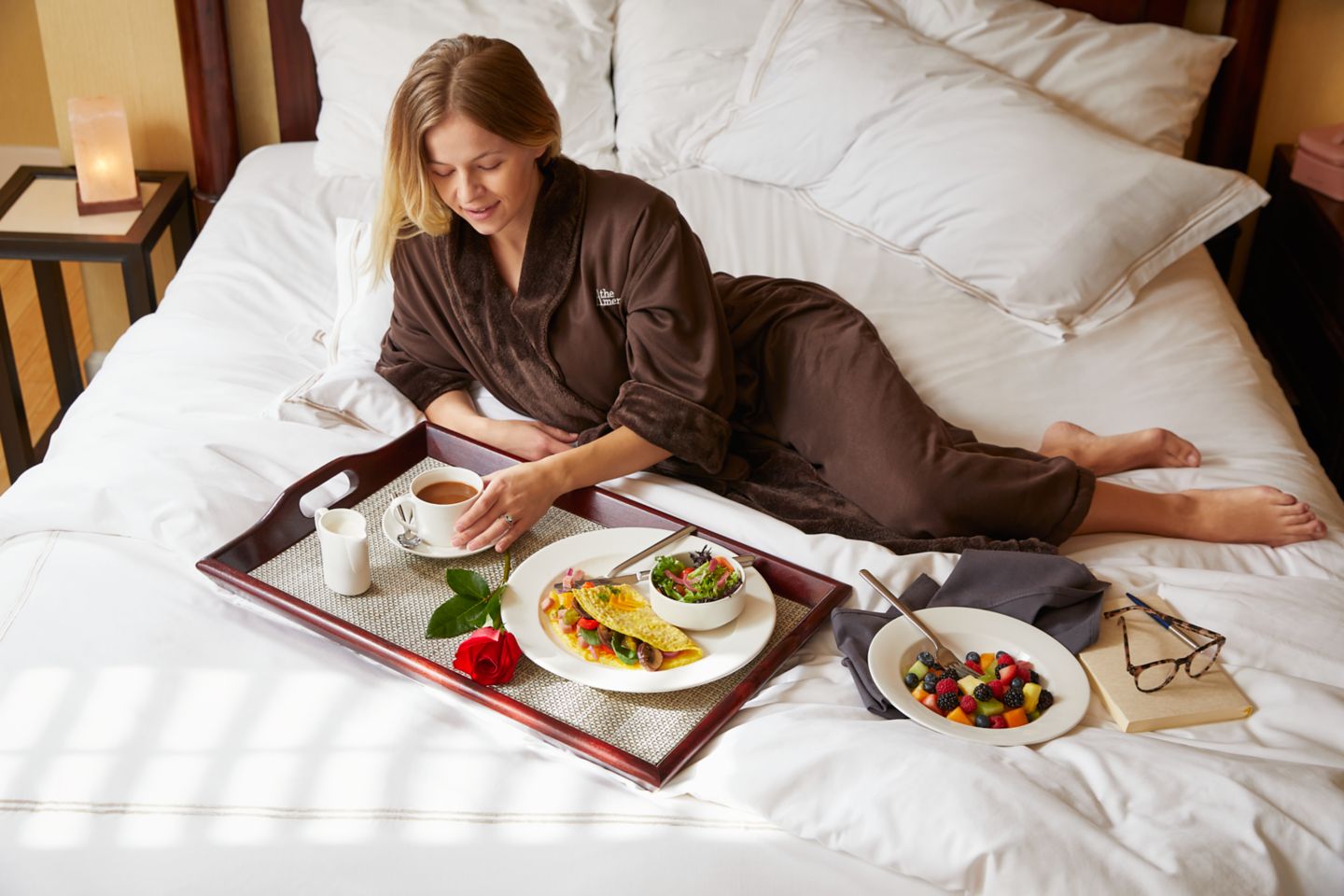 A woman having breakfast in bed while wearing a plush robe