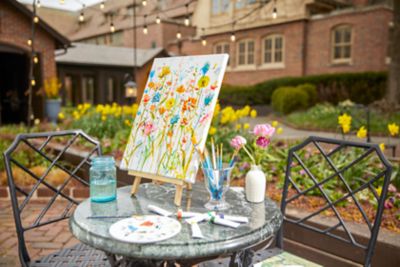 a painted canvas on a table in an outdoor courtyard 