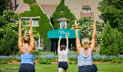 people practicing yoga on the front lawn of The American Club
