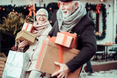 two shoppers carrying wrapped gifts