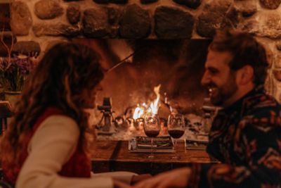 a couple enjoying wine by a roaring fireplace