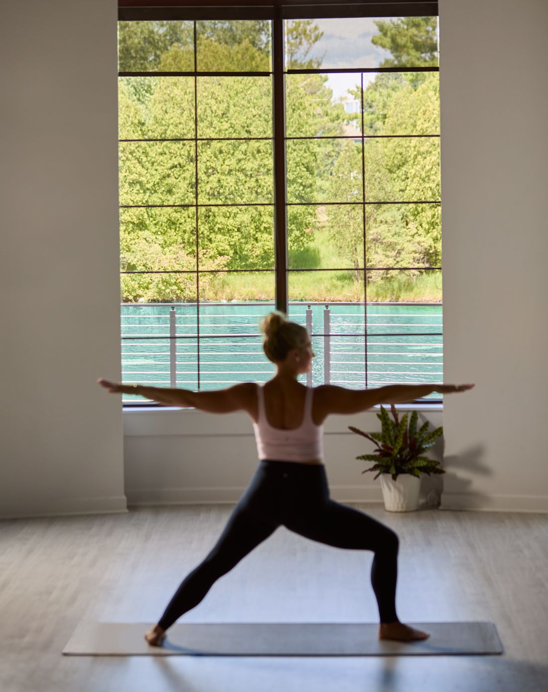 A single yogi in front of large windows