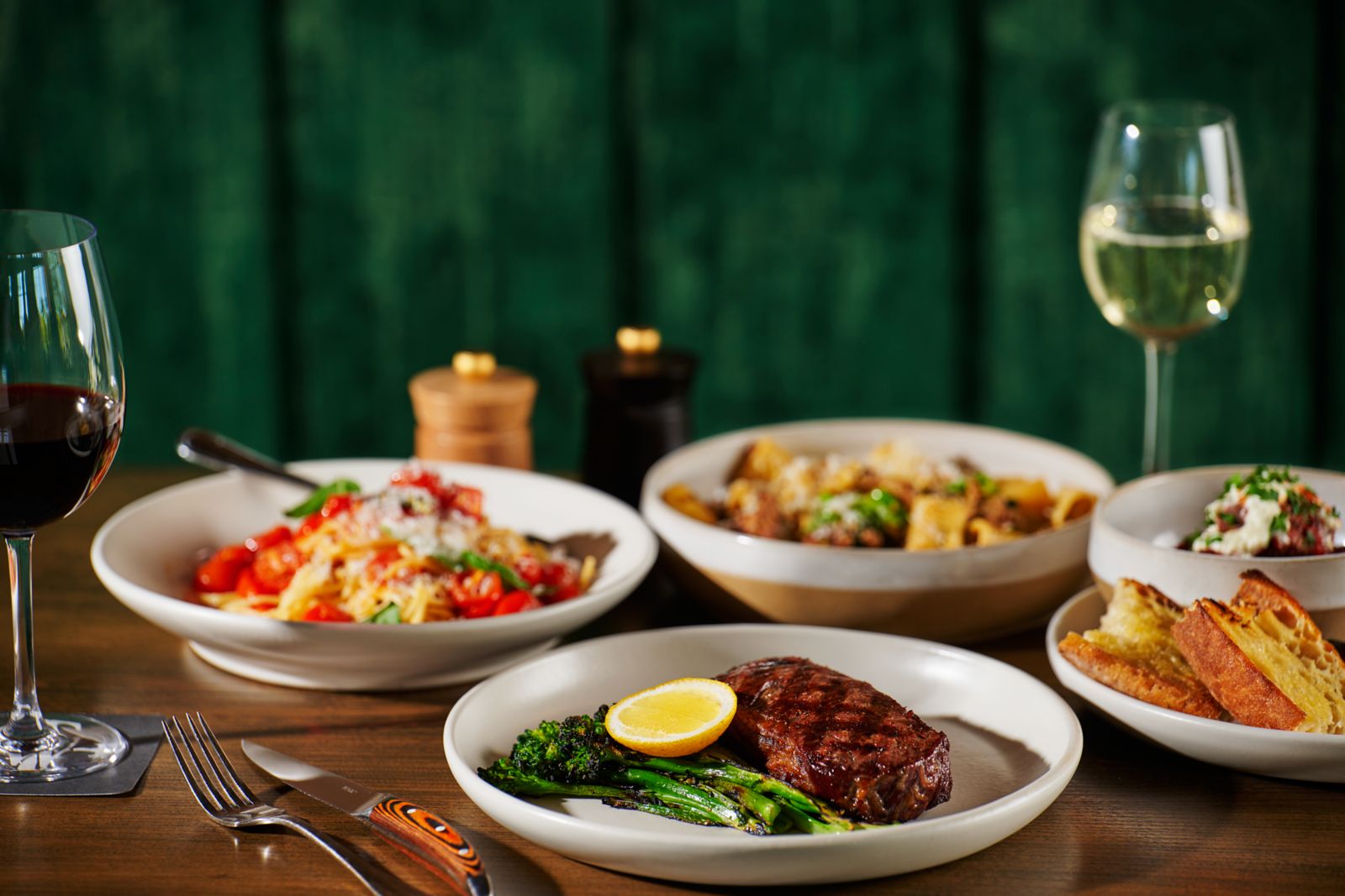 a table of food with the focus on a steak