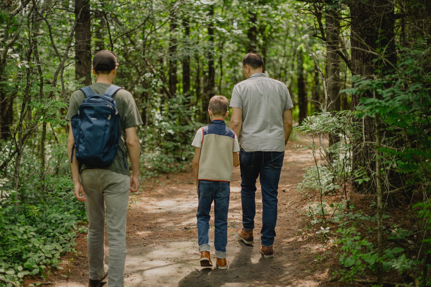 a father and two sons walking down a path