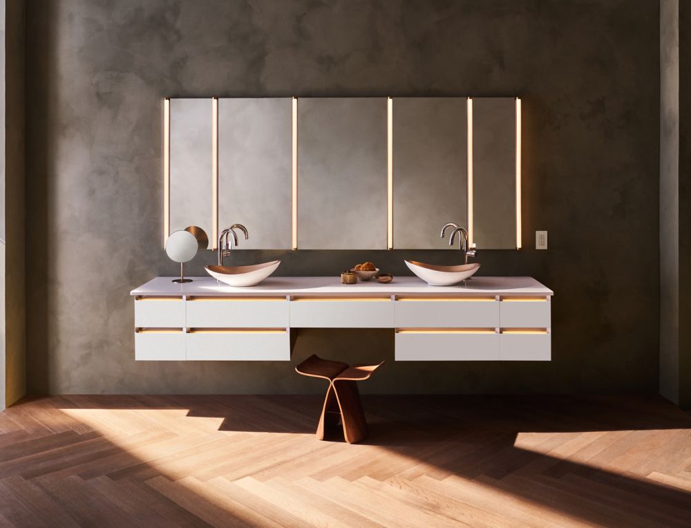 Modern double-sink bathroom vanity with wood cabinetry, illuminated mirrors, and dark stone walls.