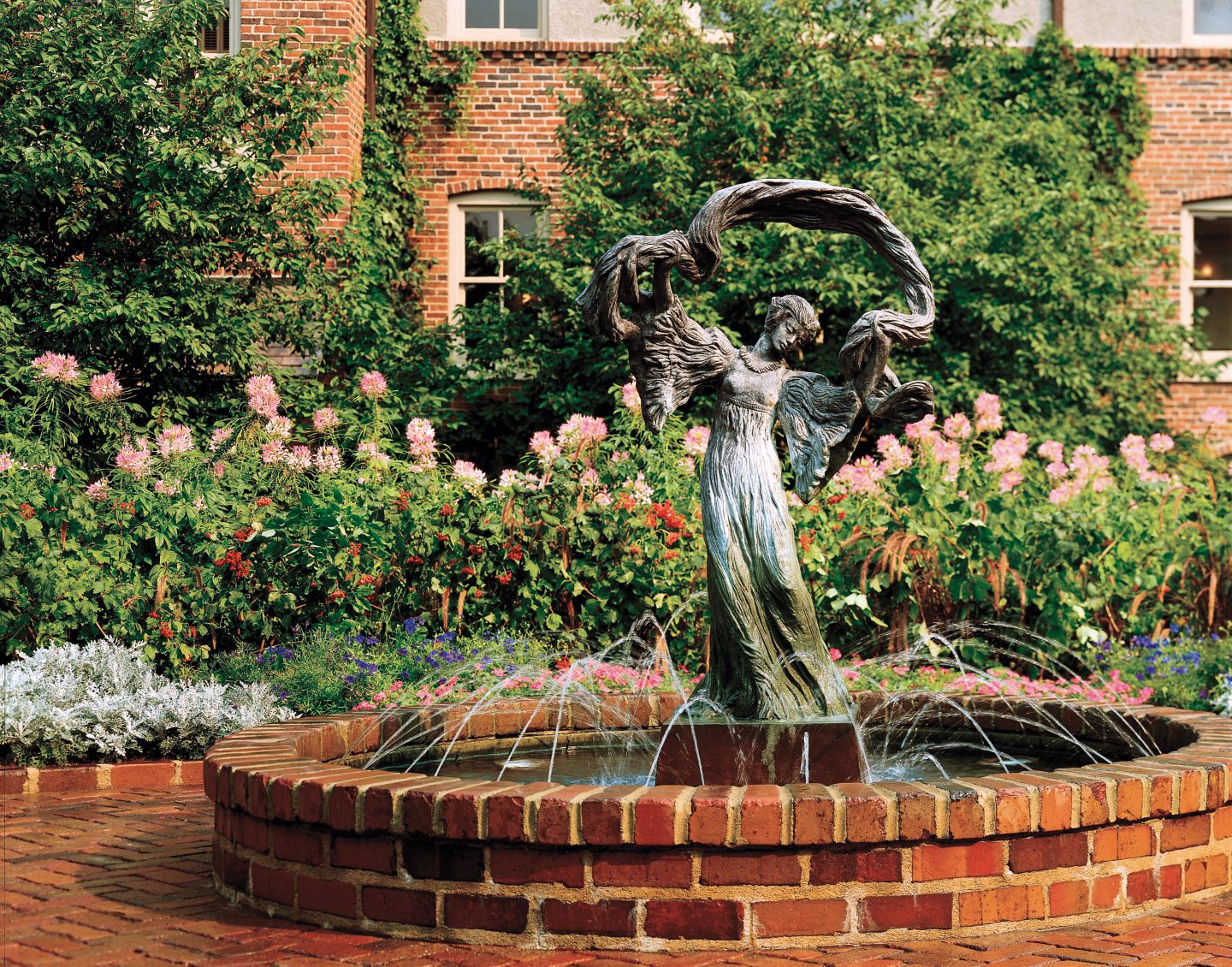 A water fountain statue of a woman with her arms up in the courtyard of The American club, 