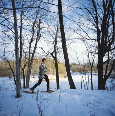 a woman snowshoeing in the woods next to a river