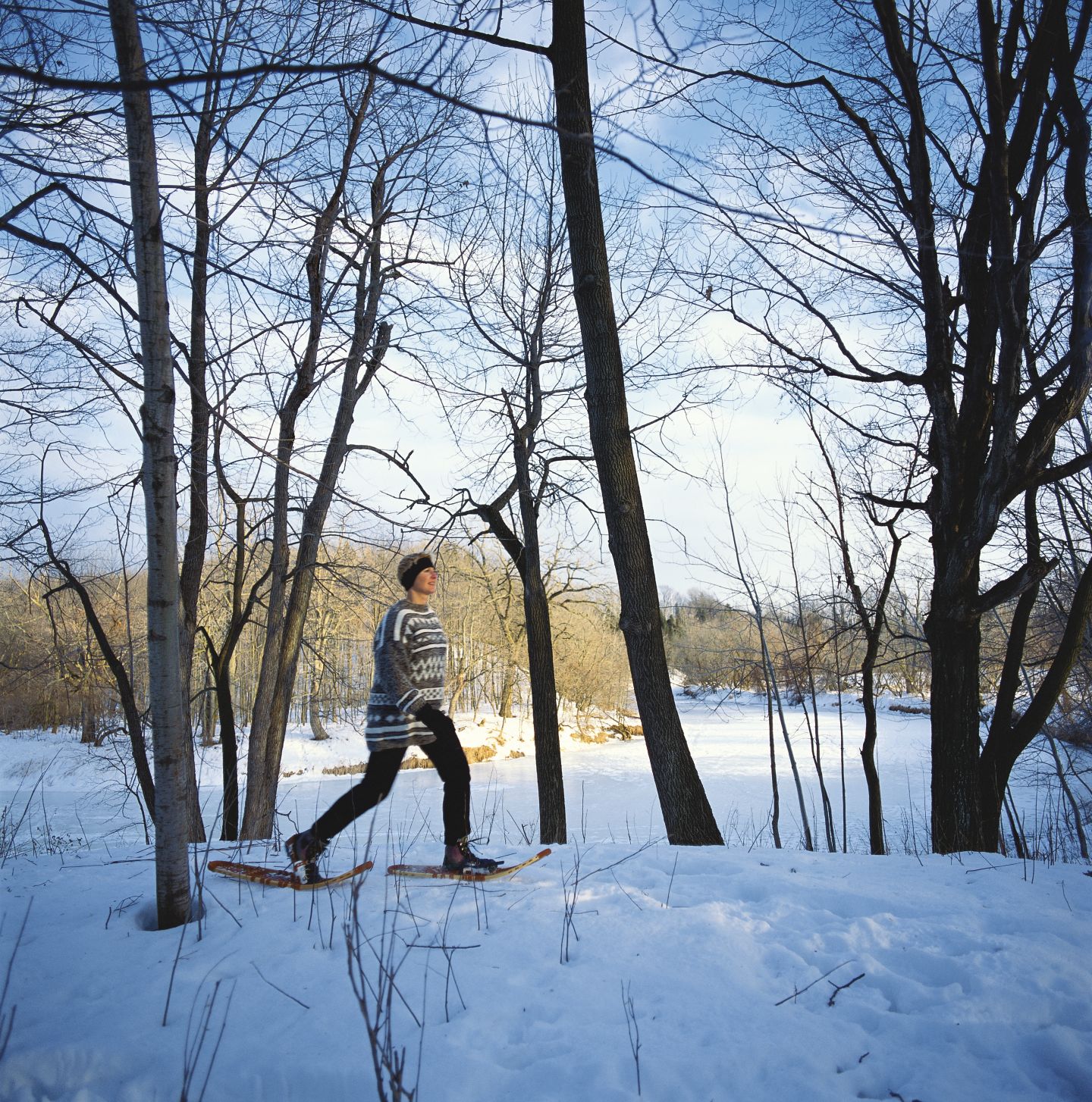 A lone snowshoer hikes near a lake in wintertime