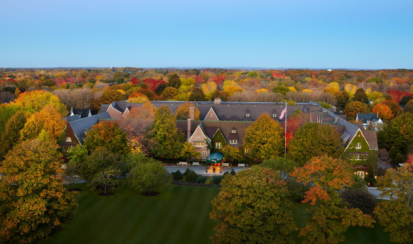 overview look of The American Club, a historic building surrounded by trees with changing leaves in fall