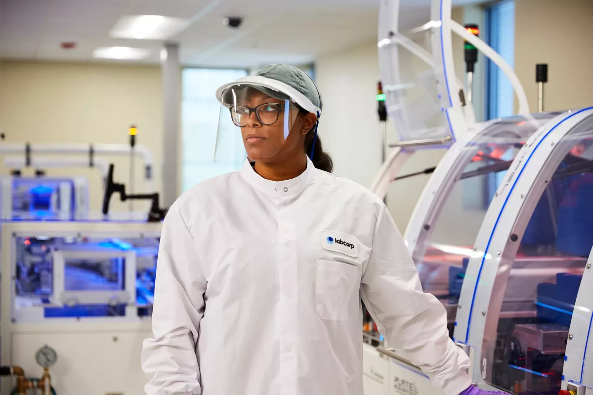 Labcorp scientist standing by a machine while wearing ppe