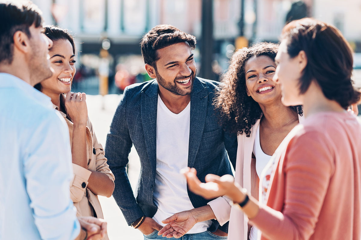 A large group of young and diverse friends chatting outside in a city street