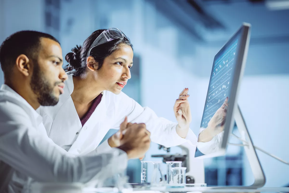 Two scientists working inside a lab observing a computer screen