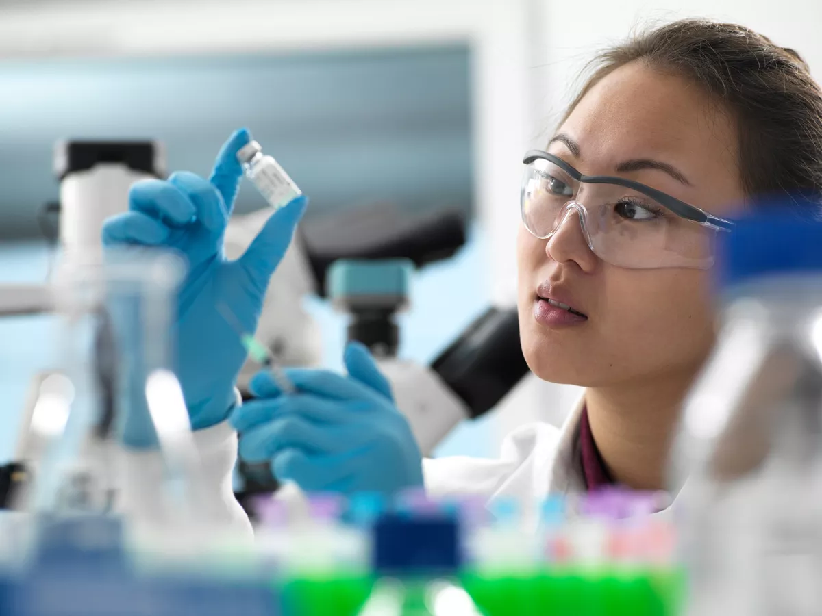 Woman scientist looking at specimen next to a microscope