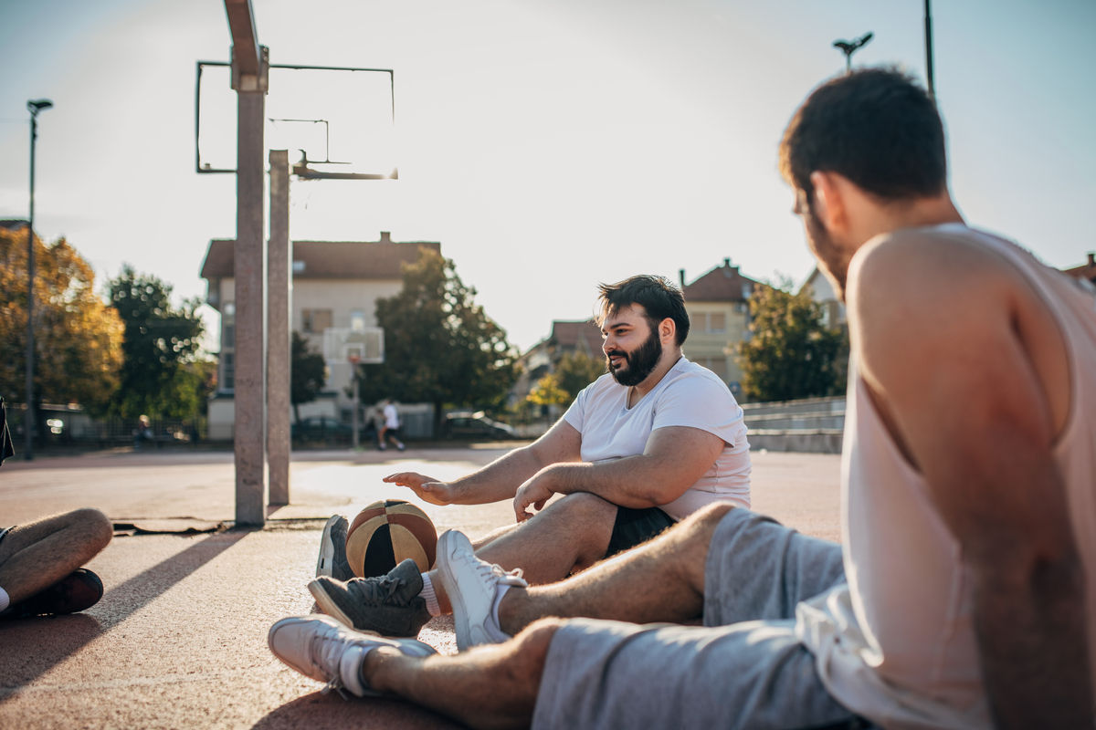 Group of men sitting on the ground after a basketball game