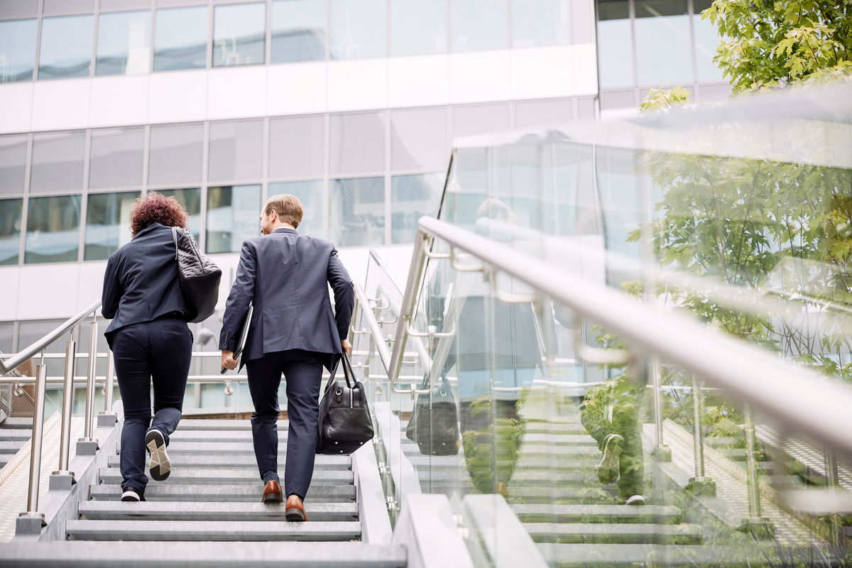 Two business people walking up staircase