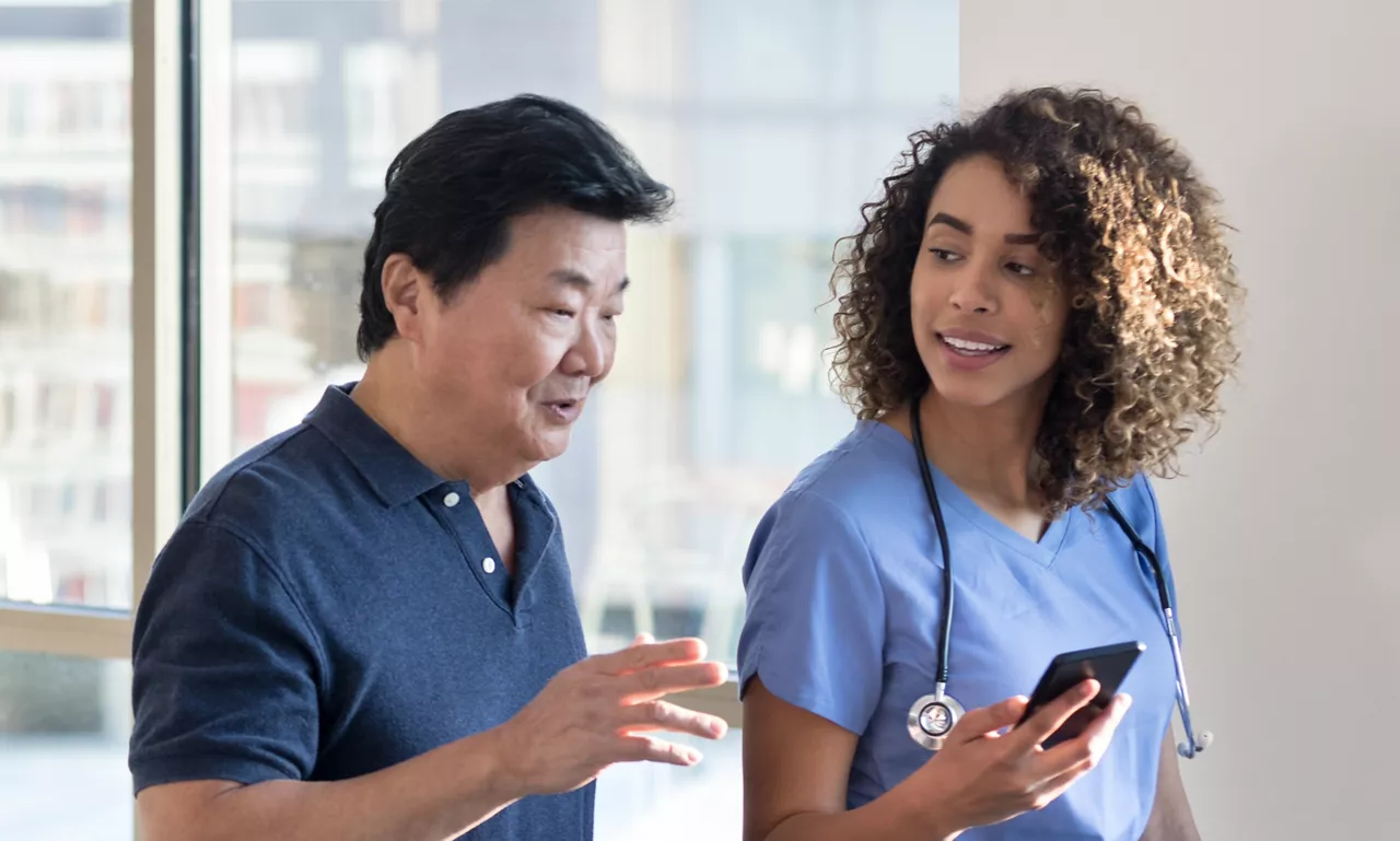 Female doctor showing male patient results on phone