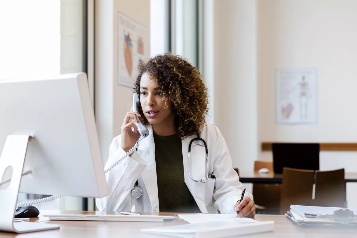 Provider calling patient and taking notes at her desk