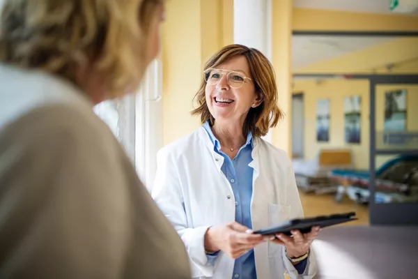 Provider standing in a hallway with tablet. She is smiling into the distance