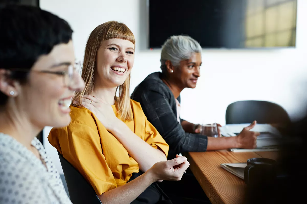 Woman in a work meeting holding onto her shoulder