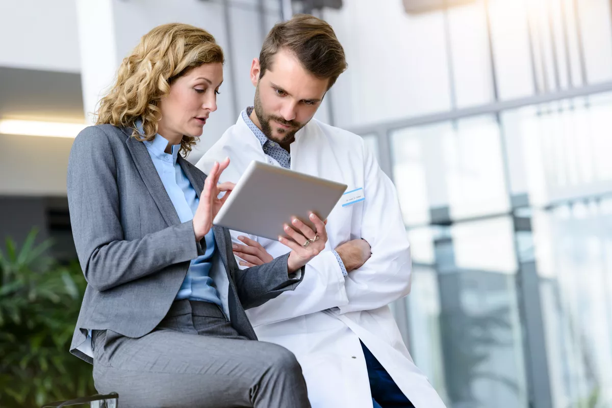 Two providers talking in an annex. They are reviewing a tablet