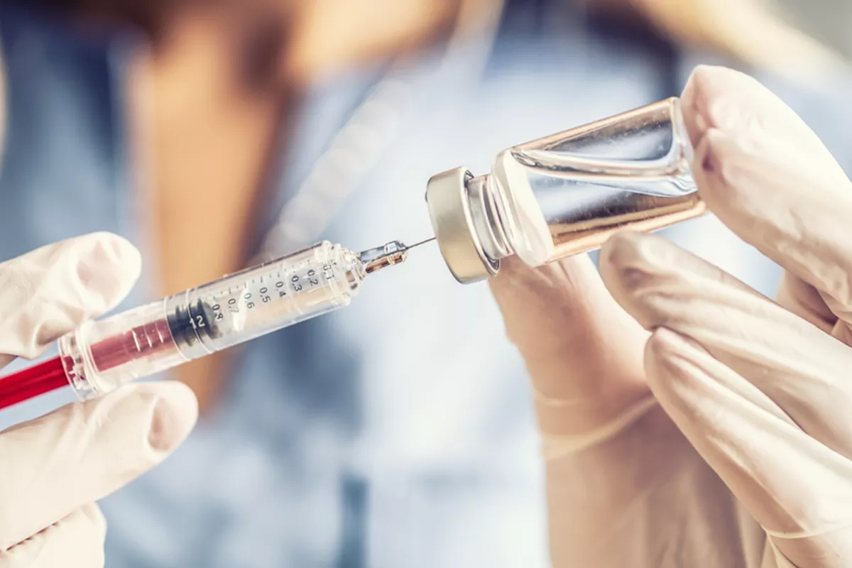 Prestataire de services extrayant une dose de vaccin à l'aide d'une aiguille