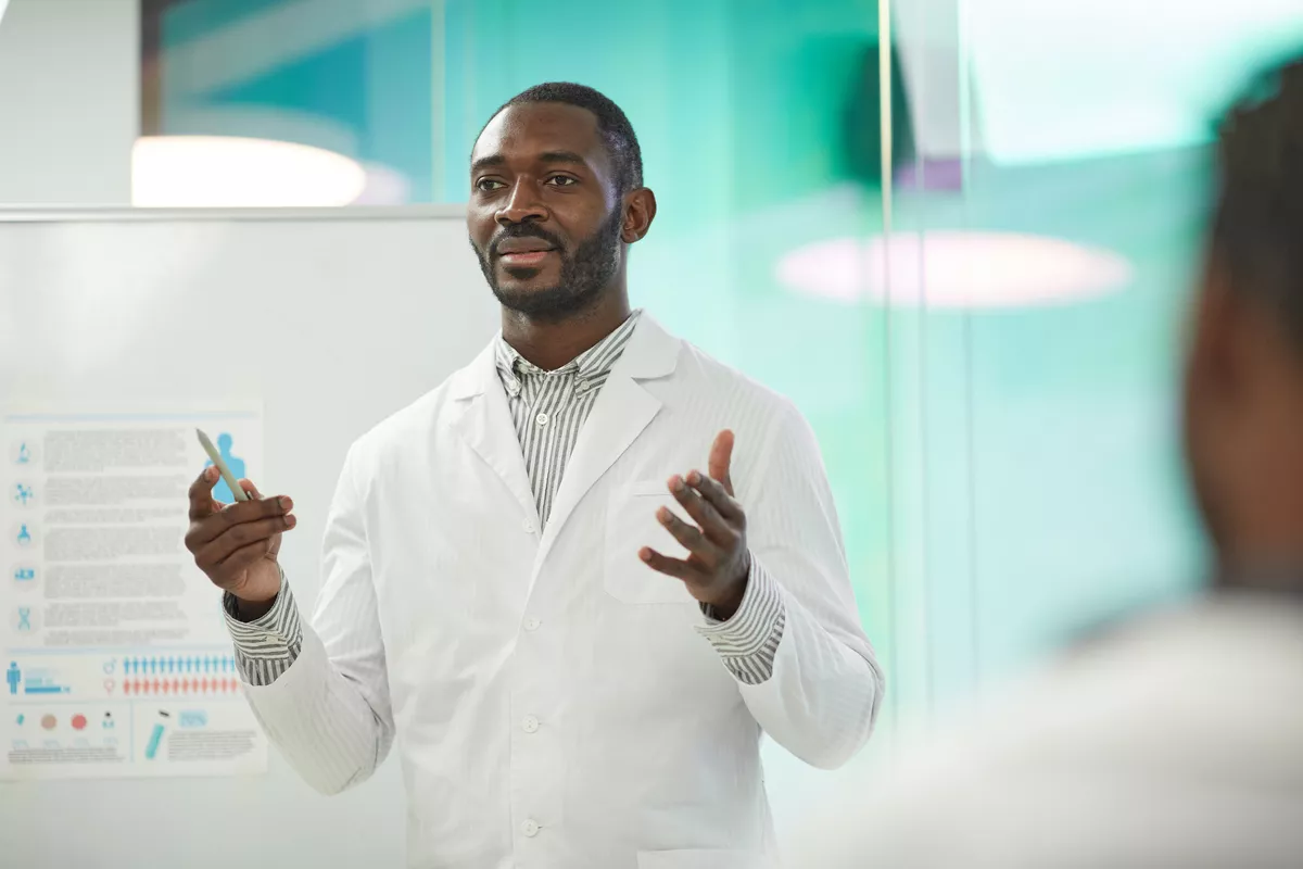 Scientist standing in front of a white board explaining his findings