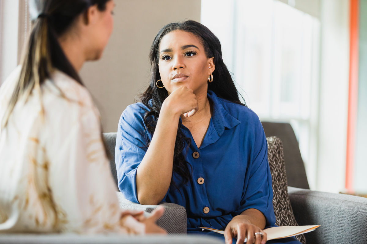 Woman sitting on a couch deep in thought while listening to a patient