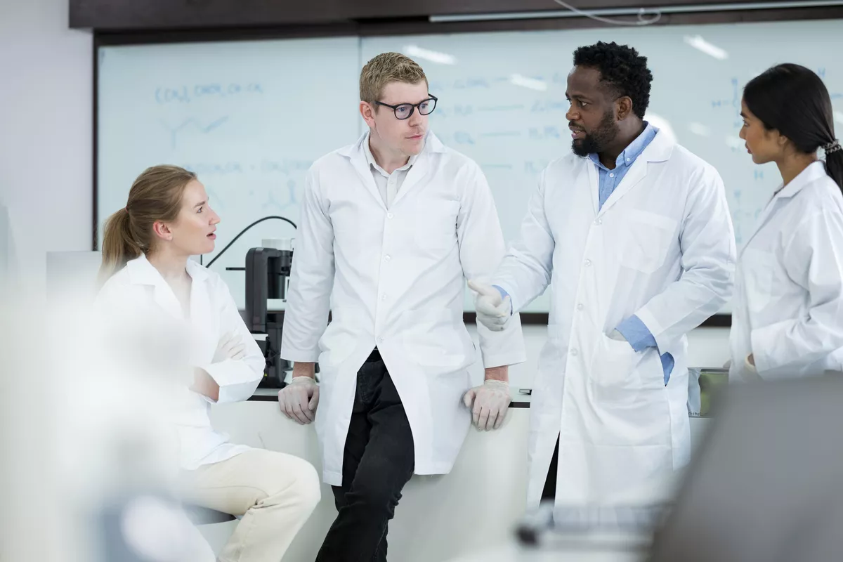 Group of four scientists talking in a lab setting
