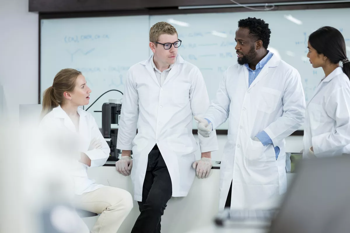 Grupo de cuatro científicos que conversan en un laboratorio