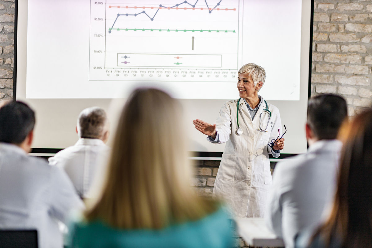 Provider presenting at a meeting pointing to a screen behind her