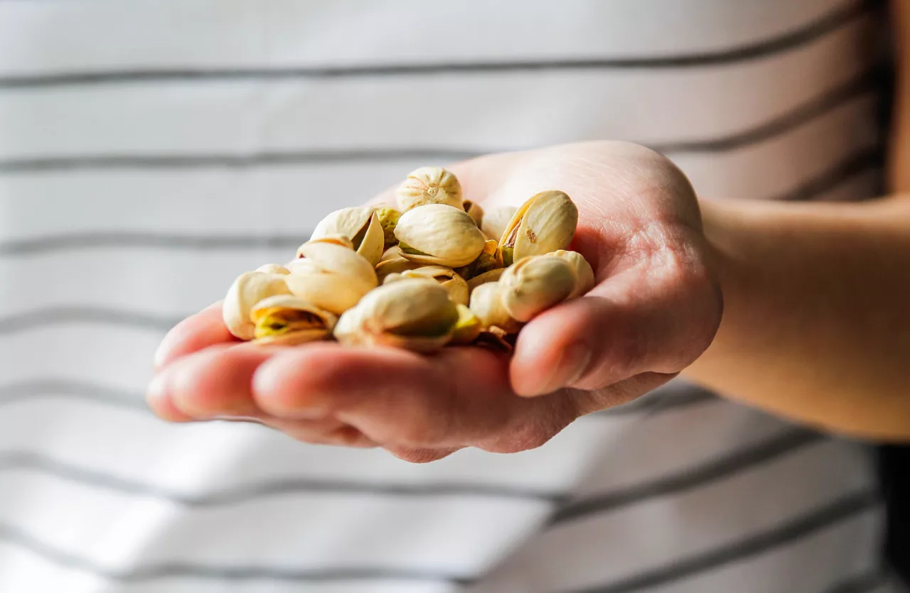 Hand extended holding pistachios