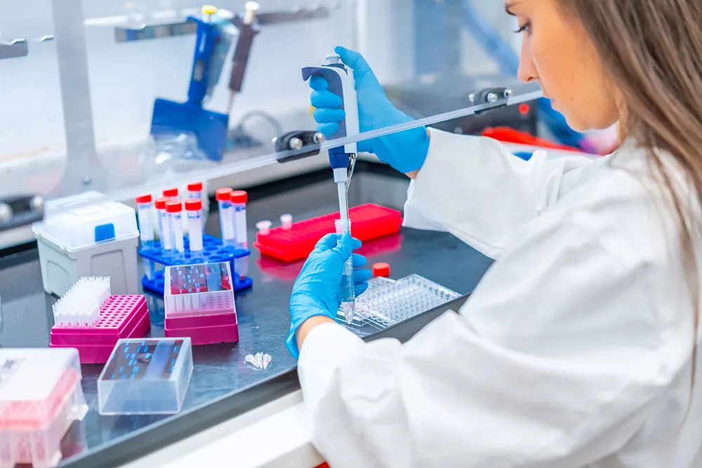 Scientist holding a pipette while extracting a specimen