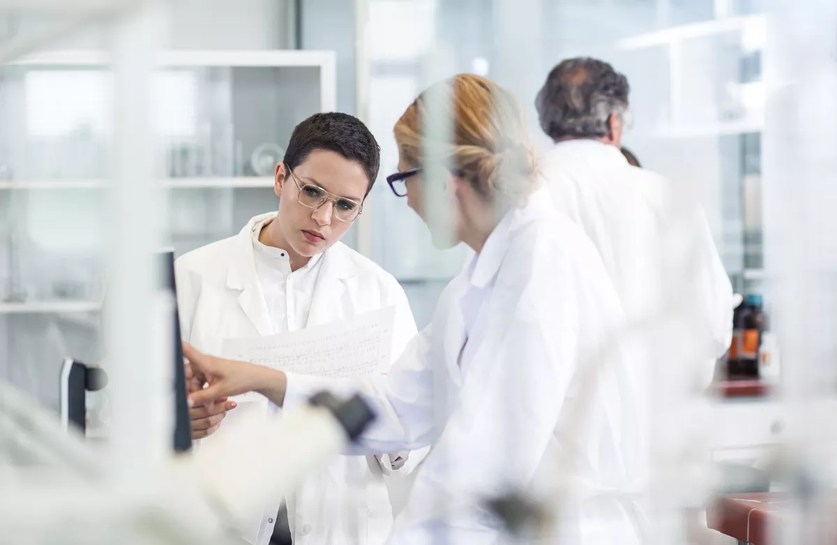 Una línea de científicos trabajan juntos en un laboratorio. Todos se centran su propia muestra