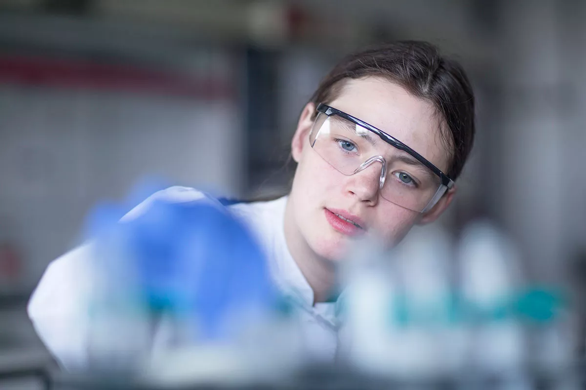 Scientist focusing in on project as she is overing over test tubes